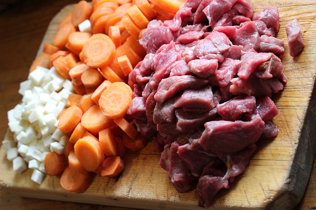 Recette Boeuf Bourguignon : Oignons, carottes et boeuf en morceaux sur une planche à découper
